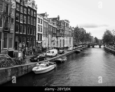 Typical water canal - gracht - and narrow houses along it in Amsterdam city centre, Netherlands, black and white image Stock Photo