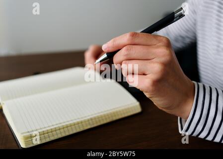 Writing by left hand in notepad. Left hander day concept Stock Photo