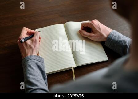 Writing by left hand in notepad. Left hander day concept Stock Photo