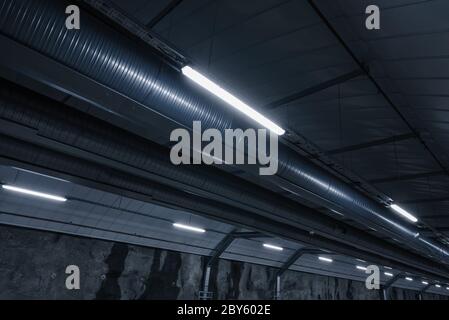 Sci fi looking dark and moody underground parking lot with fluorescent lights on.  Ceiling shot Stock Photo