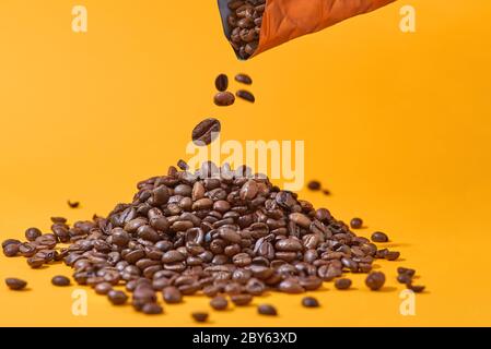 coffee beans falling on a yellow background. Contrasting colors, minimalism. Fighting prostate cancer Stock Photo