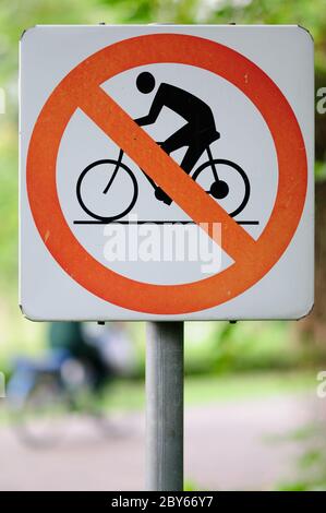 No cycling sign on a pole with a cyclist on the background Stock Photo