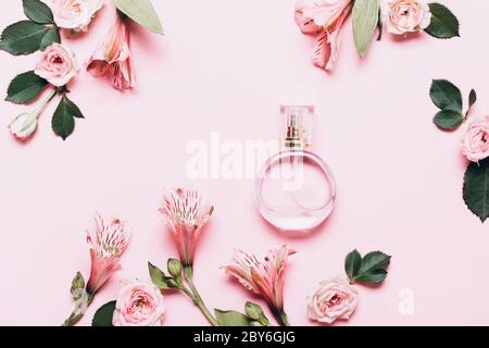 Women's perfume bottle and roses flowers on pink background. Creative Layout, copy space. Stock Photo