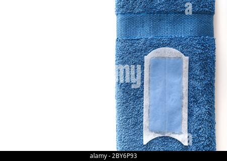 Disposable wax strip for depilation,on blue cotton towel isolated on white. Top view. Stock Photo