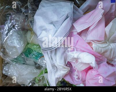 Used sanitary napkins, surgical face mask, and plastic in the trash. Infectious waste management concept. Waste separation. Unhygienic garbage trash. Stock Photo