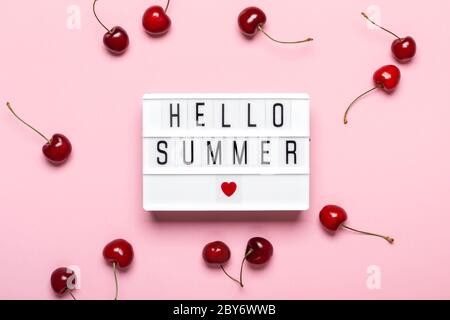 Light box with Hello Summer text and ripe cherries on pink background. Hello Summer concept. Stock Photo