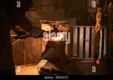 Blacksmith shaping steel on anvil in workshop Stock Photo