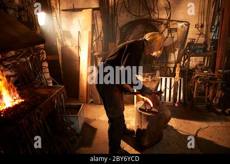 Female blacksmith working in workshop Stock Photo