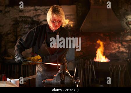 Female blacksmith working in workshop Stock Photo