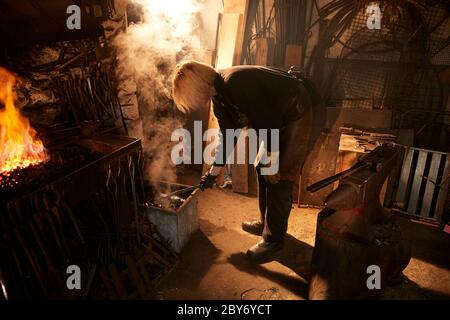 Female blacksmith working in workshop Stock Photo