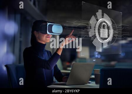 Businesswoman using virtual reality glasses at laptop Stock Photo