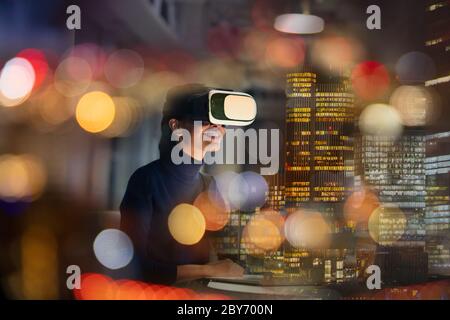 Businesswoman with virtual reality glasses in highrise office at night Stock Photo
