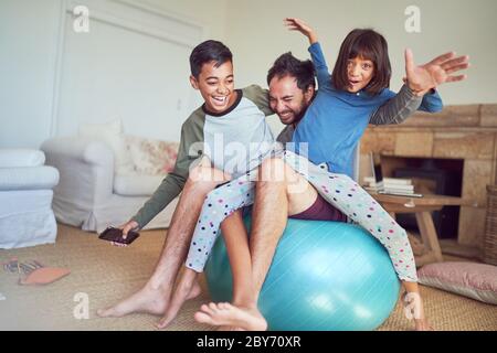 Portrait happy family playing on fitness ball in living room Stock Photo