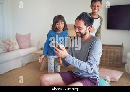 Happy father and kids with smart phone in living room