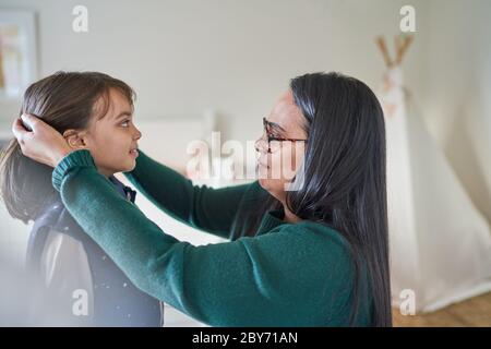 Mother helping daughter fix hair Stock Photo