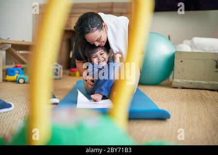 Happy mother and son playing on yoga mat Stock Photo