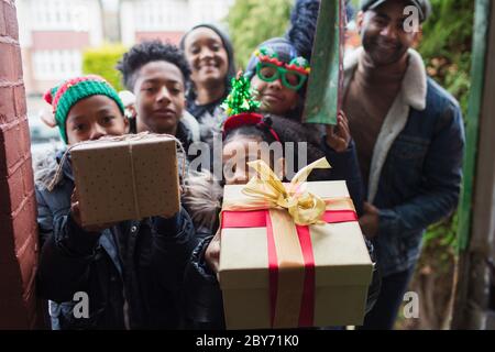 Portrait happy family delivering Christmas gifts at front stoop Stock Photo