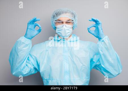 All clear. Photo of confident guy expert virologist doc center clinic professional showing okey symbol patient wear mask hazmat uniform suit facial Stock Photo