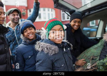 Portrait happy family loading Christmas tree in car Stock Photo