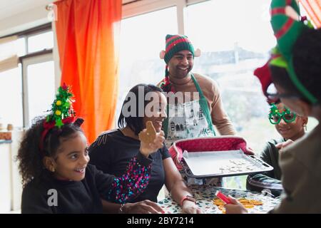 Happy family baking and eating Christmas cookies at table Stock Photo