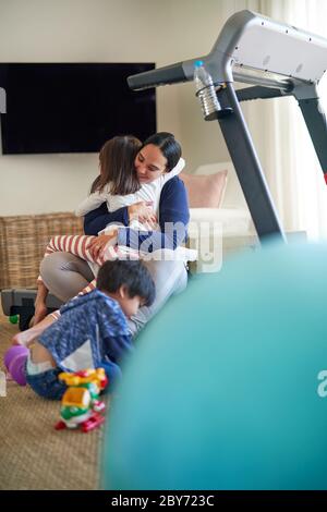 Affectionate mother and daughter hugging in living room Stock Photo