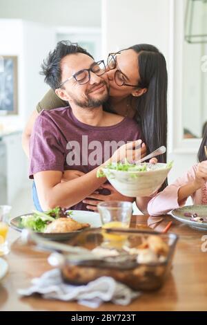 Affectionate couple kissing at dinner table Stock Photo