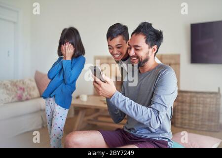 Father and kids using smart phone in living room Stock Photo