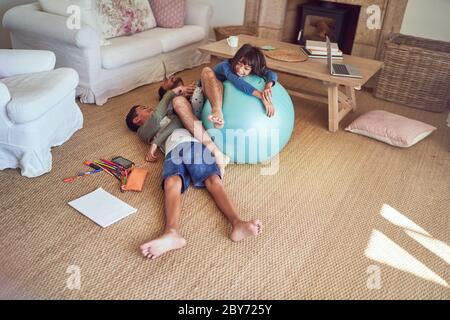 Playful father and kids with fitness ball on living room floor Stock Photo