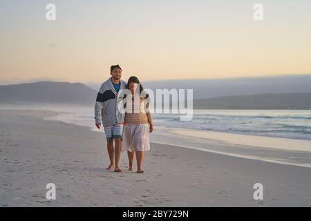 Affectionate couple walking on tranquil ocean beach Stock Photo