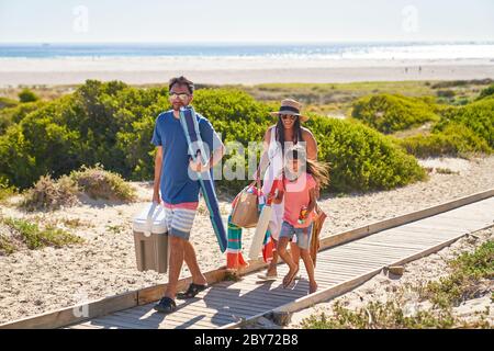 Happy family walking on sunny beach boardwalk