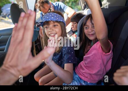 Happy kids high-fiving in back seat of car Stock Photo