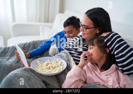 Mother and kids with popcorn watching movie on digital tablet Stock Photo