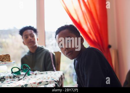 Portrait serious brothers at dining table Stock Photo