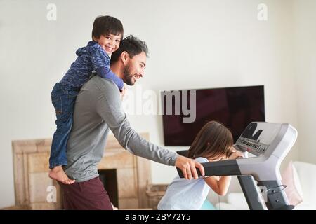 Playful kids on treadmill with father Stock Photo