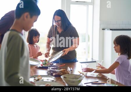 Family clearing food and dishes from lunch table Stock Photo