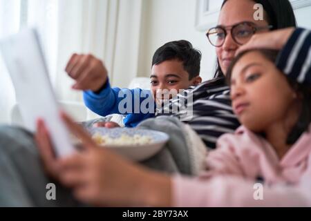 Mother and kids with popcorn watching movie on digital tablet Stock Photo