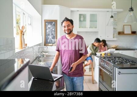 Portrait happy father working at laptop in kitchen with kids eating Stock Photo