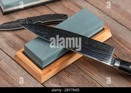 Sharpening a Japanese Gyuto knife and a jackknife with a whetstone Stock Photo