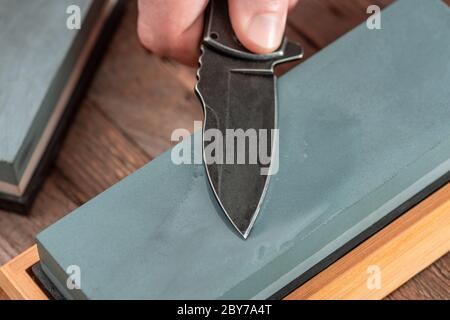 Close-up on a pocket knife being sharpened with a wet whetstone Stock Photo
