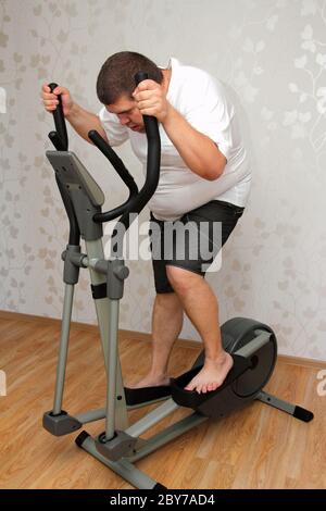 overweight man exercising on trainer Stock Photo