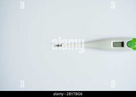 Digital body thermometer lying on a gray background. Medical thermometers. Stock Photo