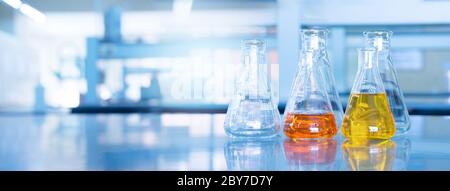 orange yellow solution in science glass flask win blue research chemistry laboratory banner background Stock Photo