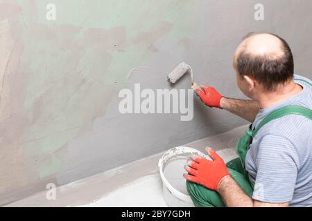 Bathroom renovation. Construction worker. Mineral moisture insulation. During work. Stock Photo