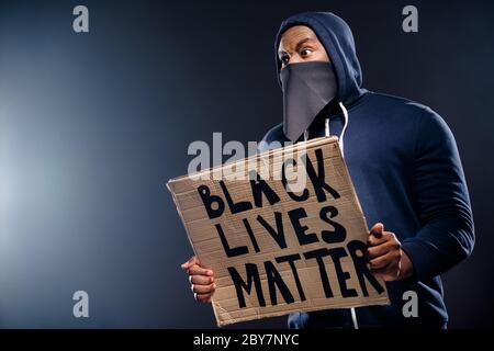 Profile side photo of shocked afro american guy hold banner impressed police community injustice racism issues wear sweater jumper isolated over black Stock Photo