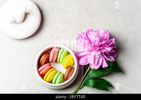 French macaroon cake. Macaroons in box with pink peony flower on grey background flat lay. Holidays, feminine desk, present concept. Top view Stock Photo