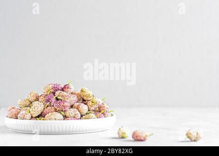 Fresh ripe white mulberries in a ceramic bowl on the table close-up. Selective focus. Space for text Stock Photo