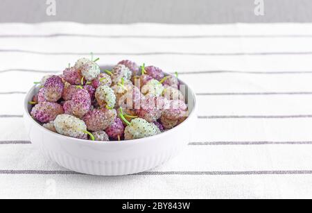 Fresh ripe white mulberries in a ceramic bowl on the table close-up. Selective focus. Space for text Stock Photo