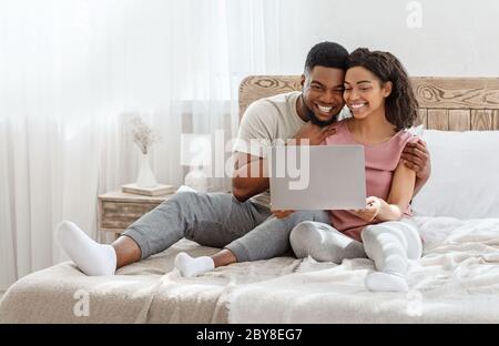 Couple in love watching photos on laptop in bedroom Stock Photo