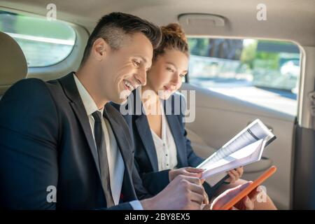 Man with tablet and woman discussing business in car. Stock Photo