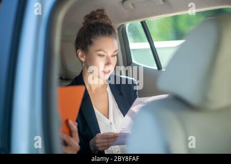 Serious business woman studying a document in a car. Stock Photo